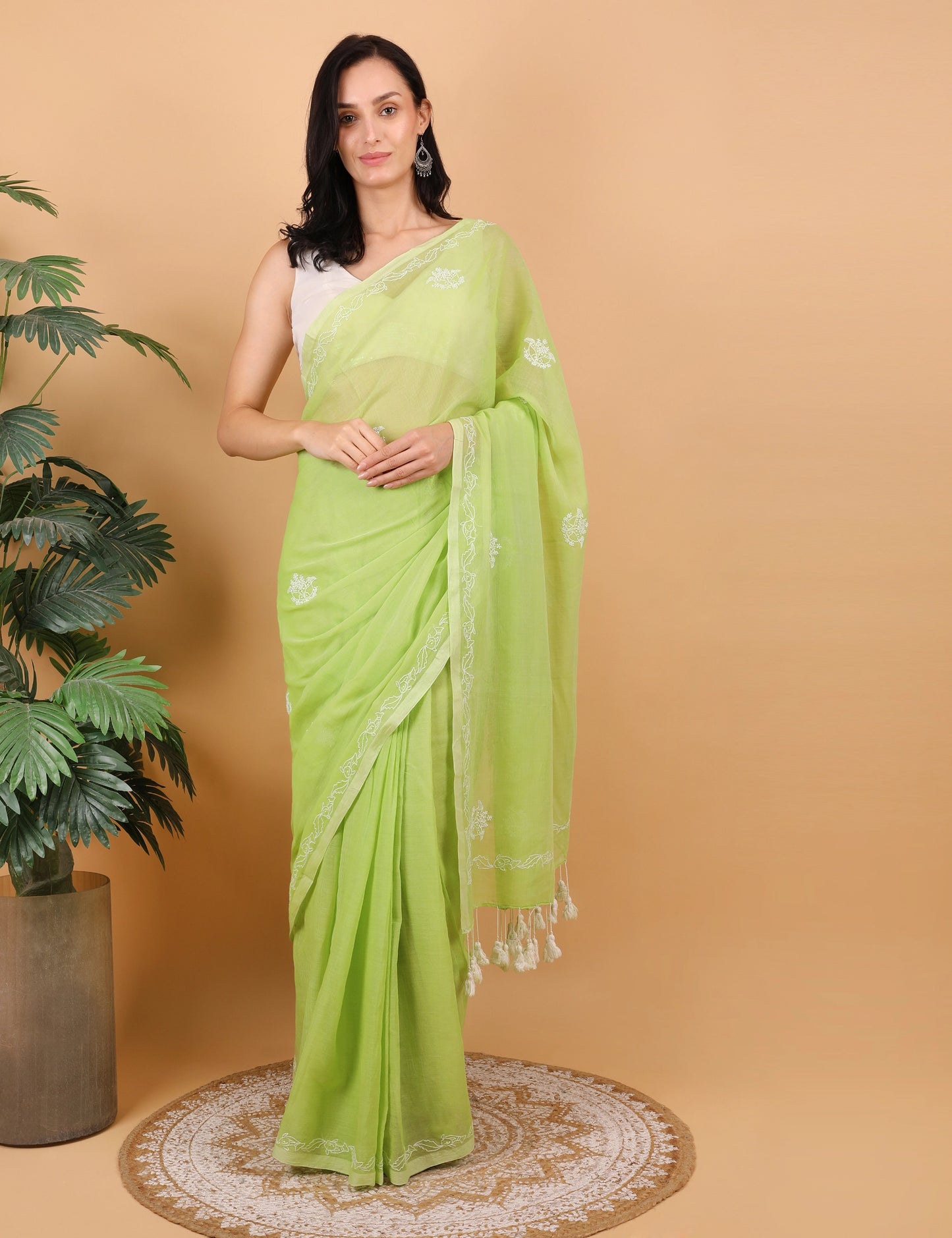 Woman wearing a light green Mulmul saree with a beige background