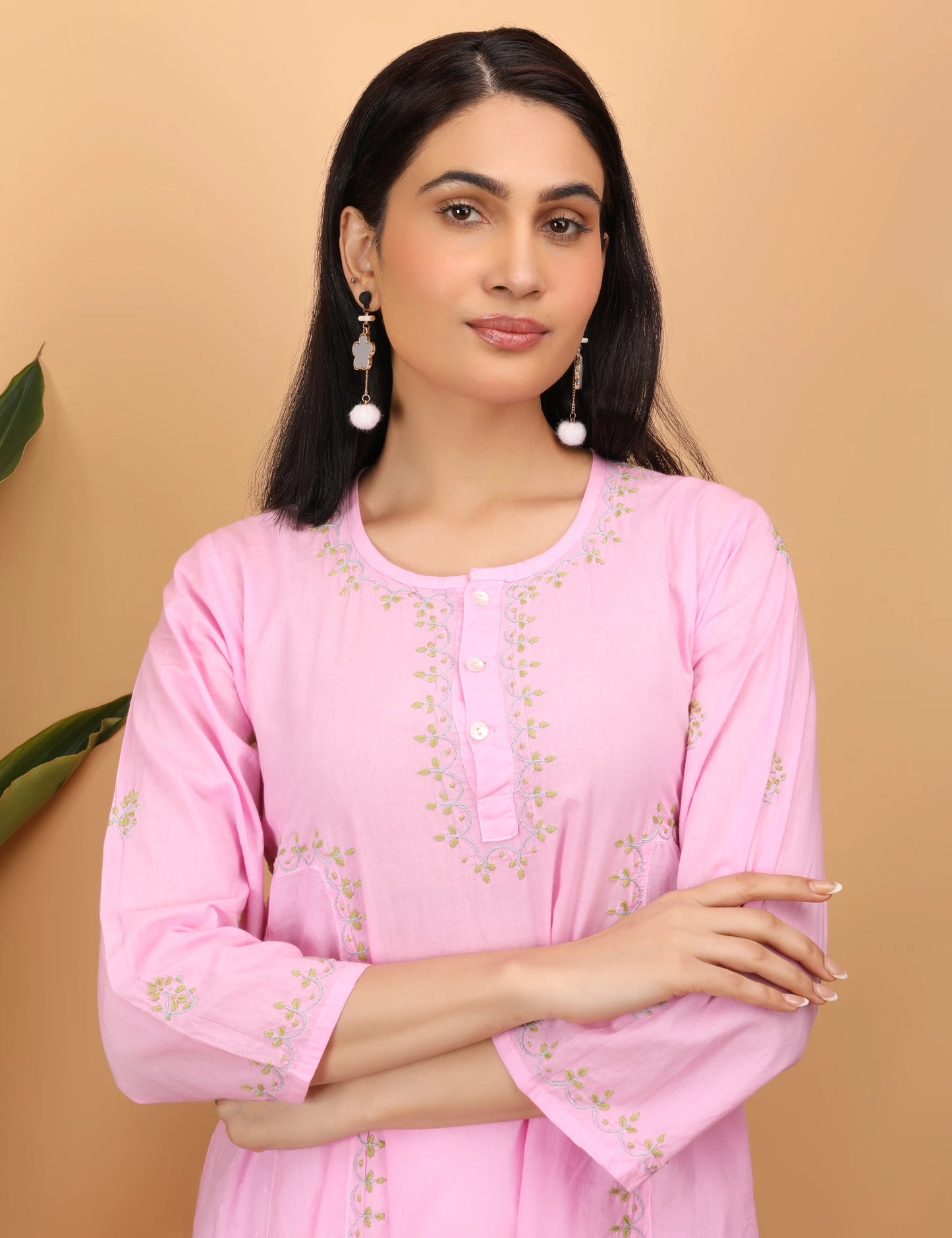 Woman wearing a pink embroidered kurta against a beige background