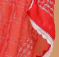 Red fabric with white lace trim on a beige background