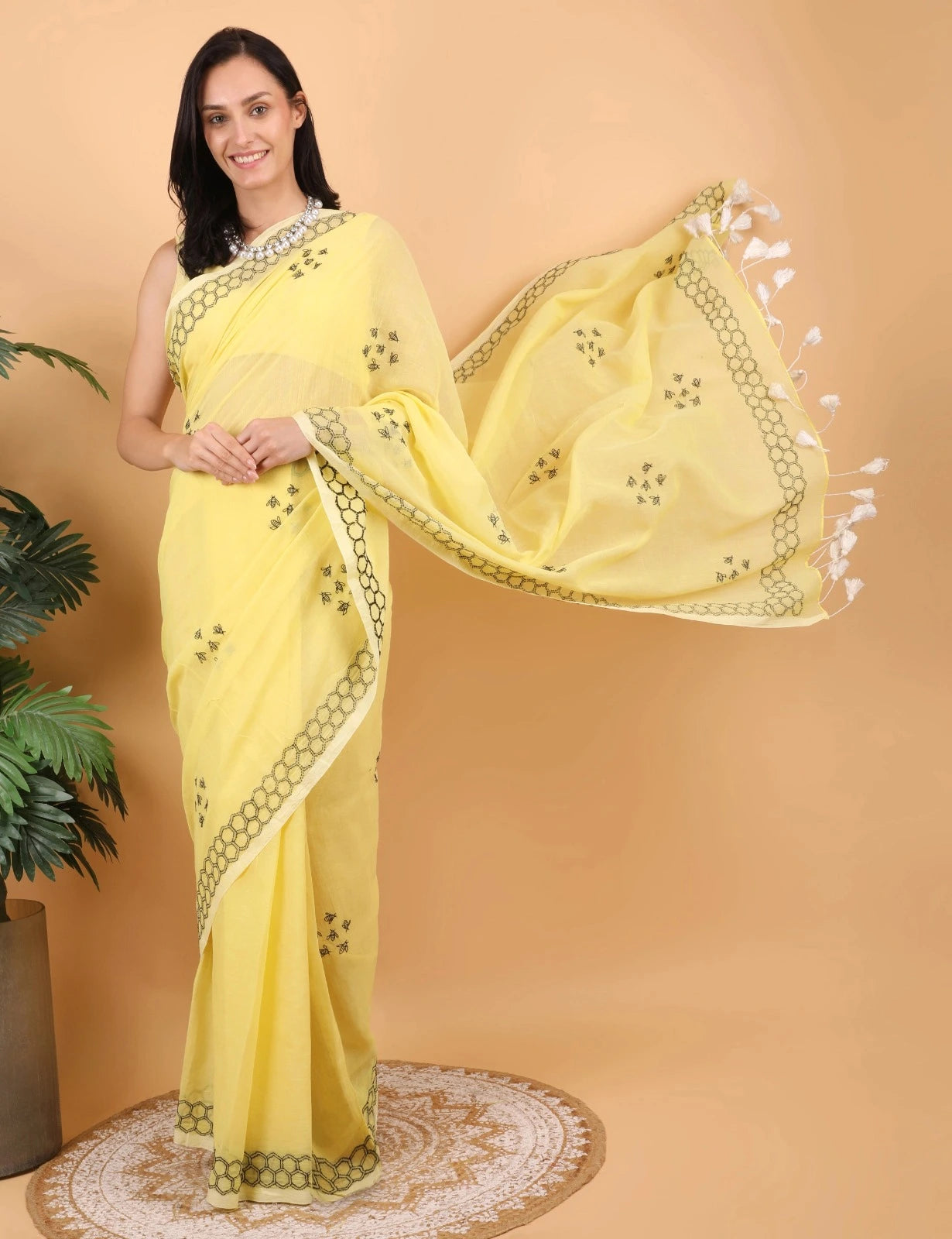 Woman wearing a yellow Mulmul saree with a beige background