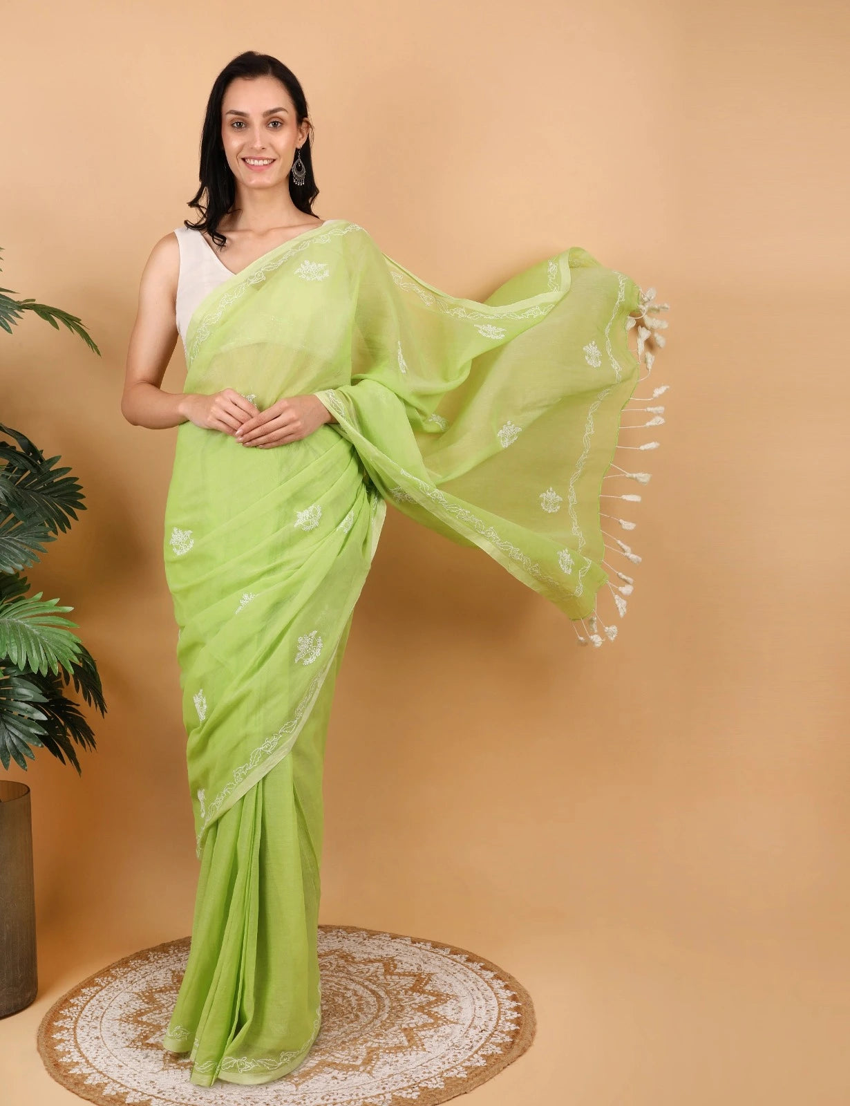 Woman wearing a light green Mulmul saree with a beige background