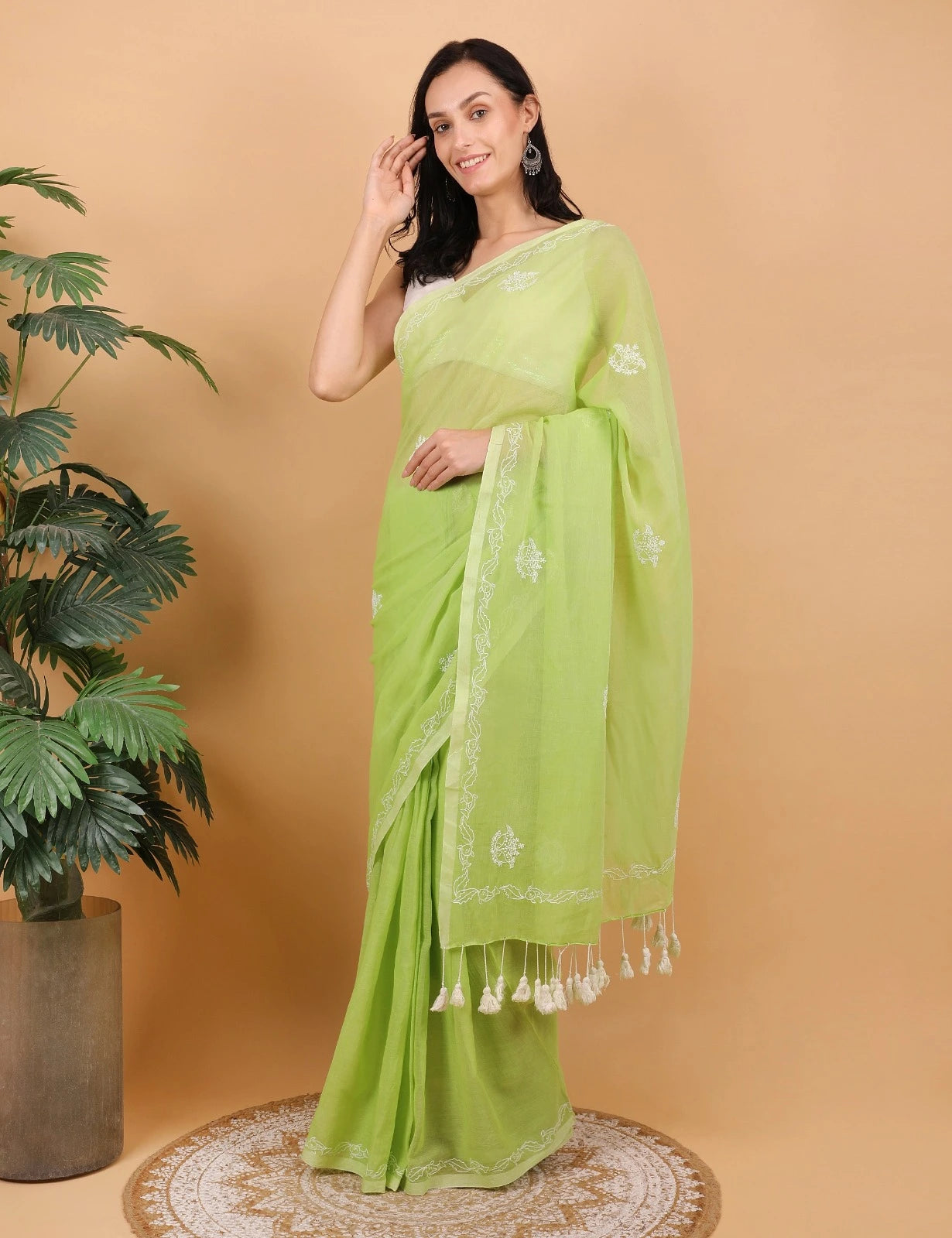 Woman wearing a light green Mulmul saree with white patterns on a beige background