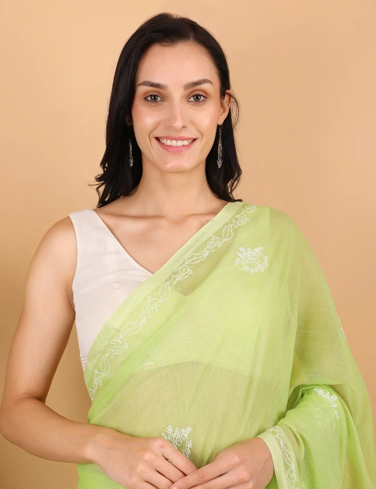 Woman wearing a light green Mulmul saree with a beige background