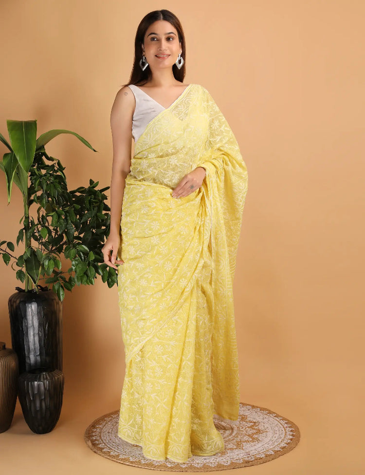 Woman wearing a yellow Hand Embroidered Chikankari saree with a white background