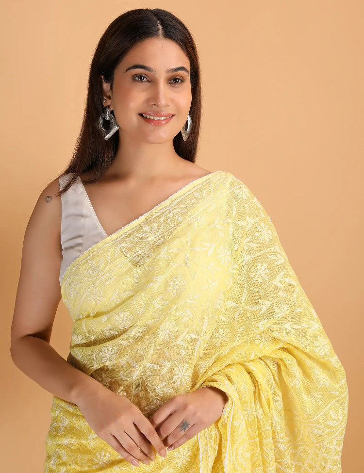 Woman wearing a yellow HAnd Embroidered Chikankari saree with a beige background