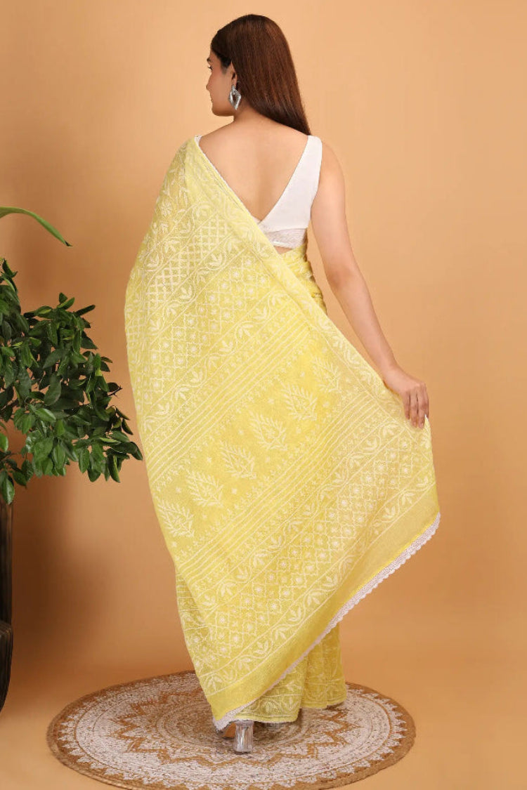 Woman wearing a yellow Hand Embroidered Chikankari saree with a white blouse against a beige background