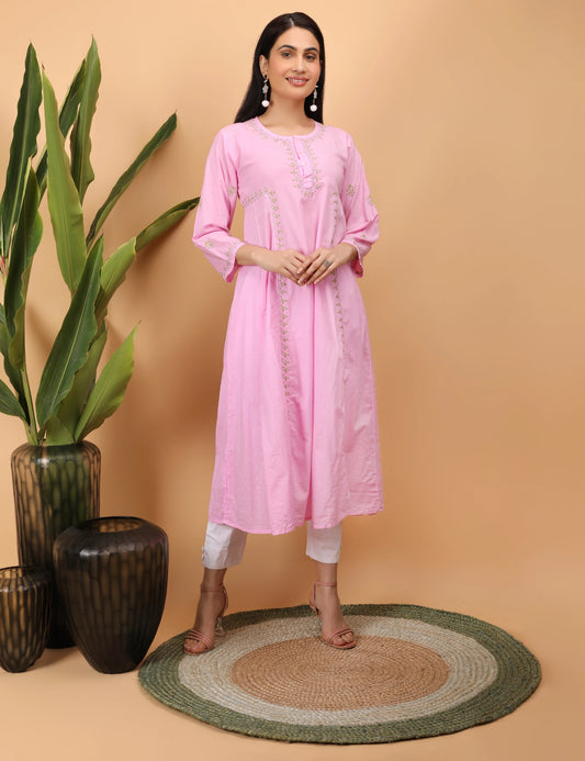 Woman wearing a pink kurta standing next to decorative vases and a plant on a beige background