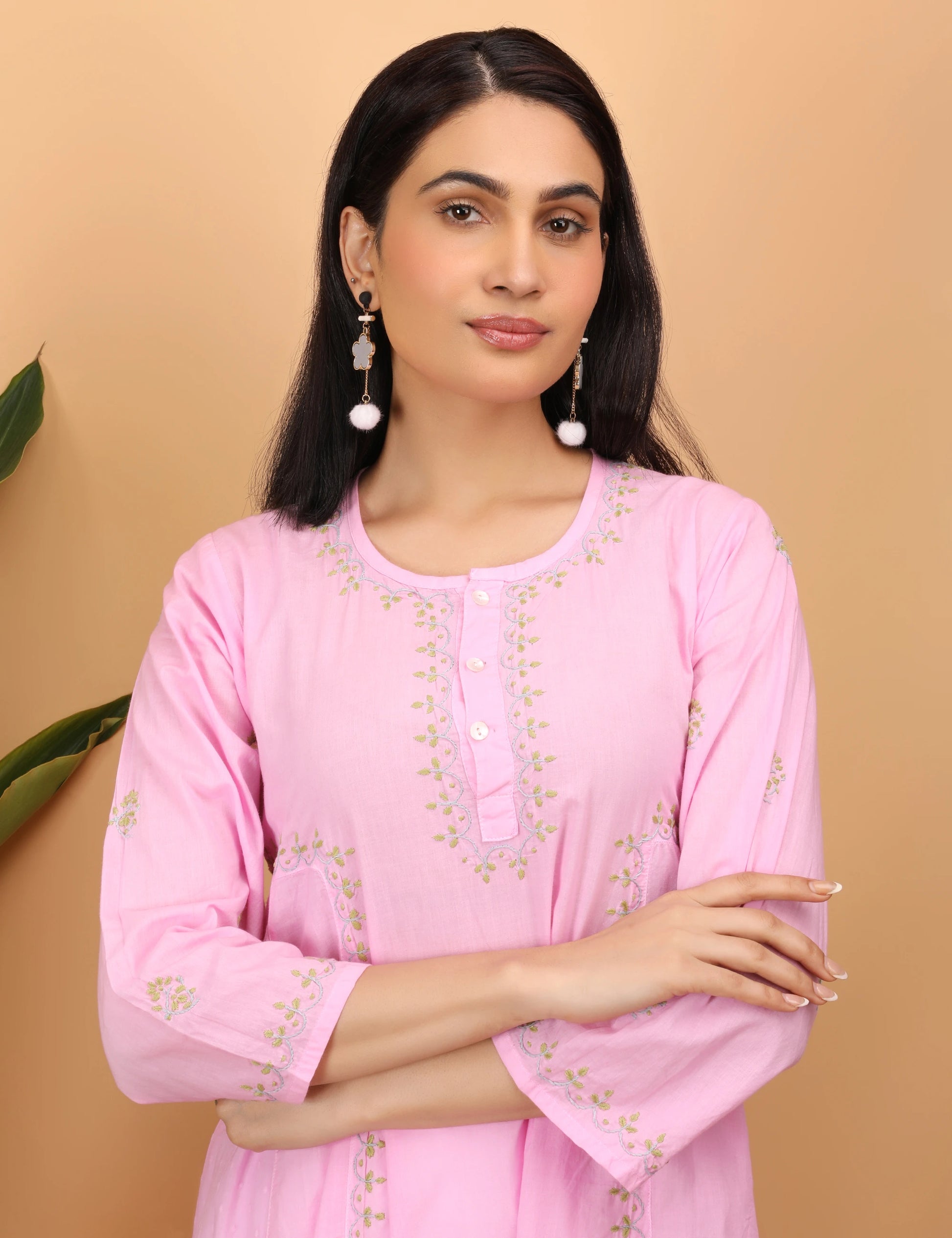 Woman wearing a pink embroidered kurta against a beige background