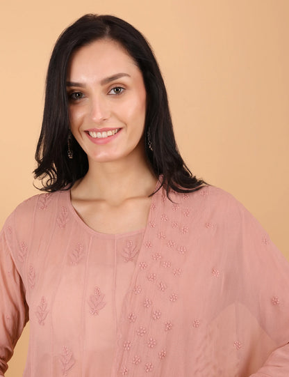 Woman wearing a Peach hand embroidered top against a beige background