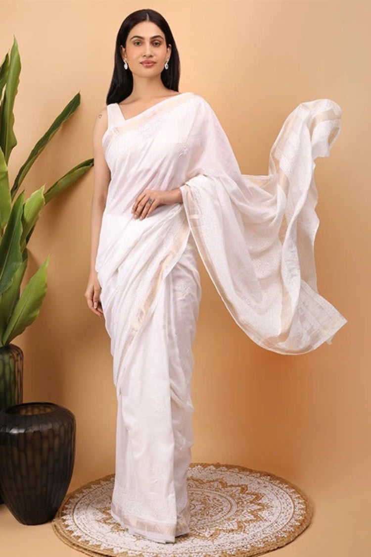 Woman wearing a white  Hand Embroidered Chikankari saree with a beige background