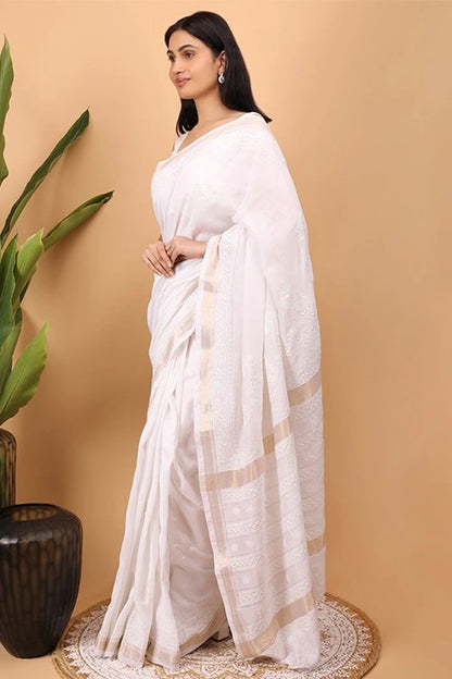 Woman wearing a whiteHand Embroidered Chikankari  saree with a beige background