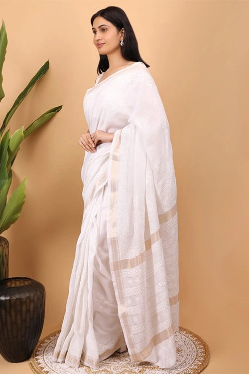 Woman wearing a whiteHand Embroidered Chikankari  saree with a beige background