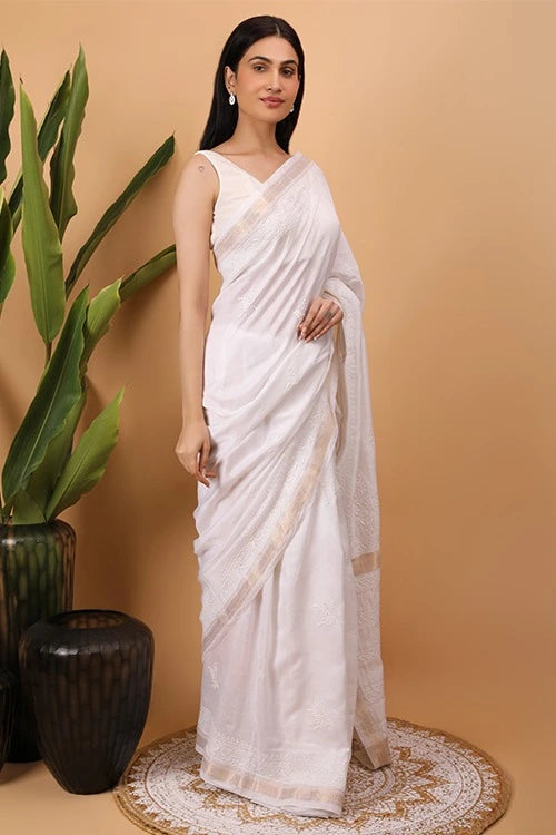 Woman wearing a white  Hand Embroidered chikankari saree with a beige background