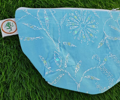 Blue pouch with white Chikankari patterns on grass