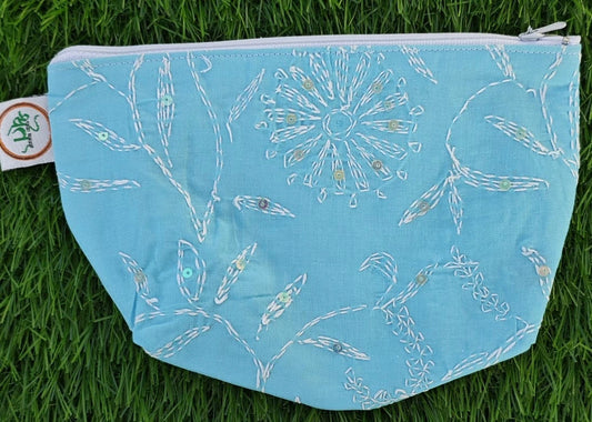 Light blue pouch with white Chikankari pattern on grass