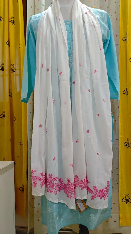 White scarf with pink chikankari embroidery draped over a person wearing a blue outfit against a yellow and white patterned background.