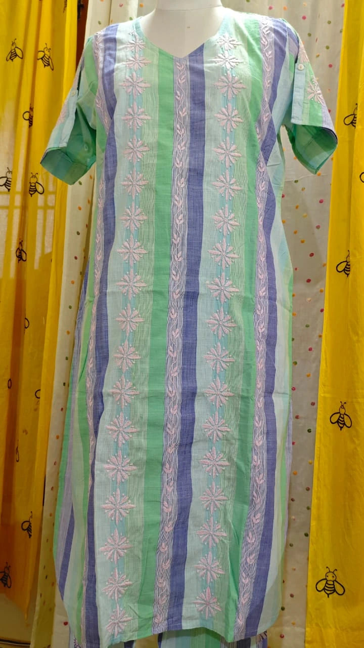 Green and purple patterned dress on a mannequin against a yellow curtain background