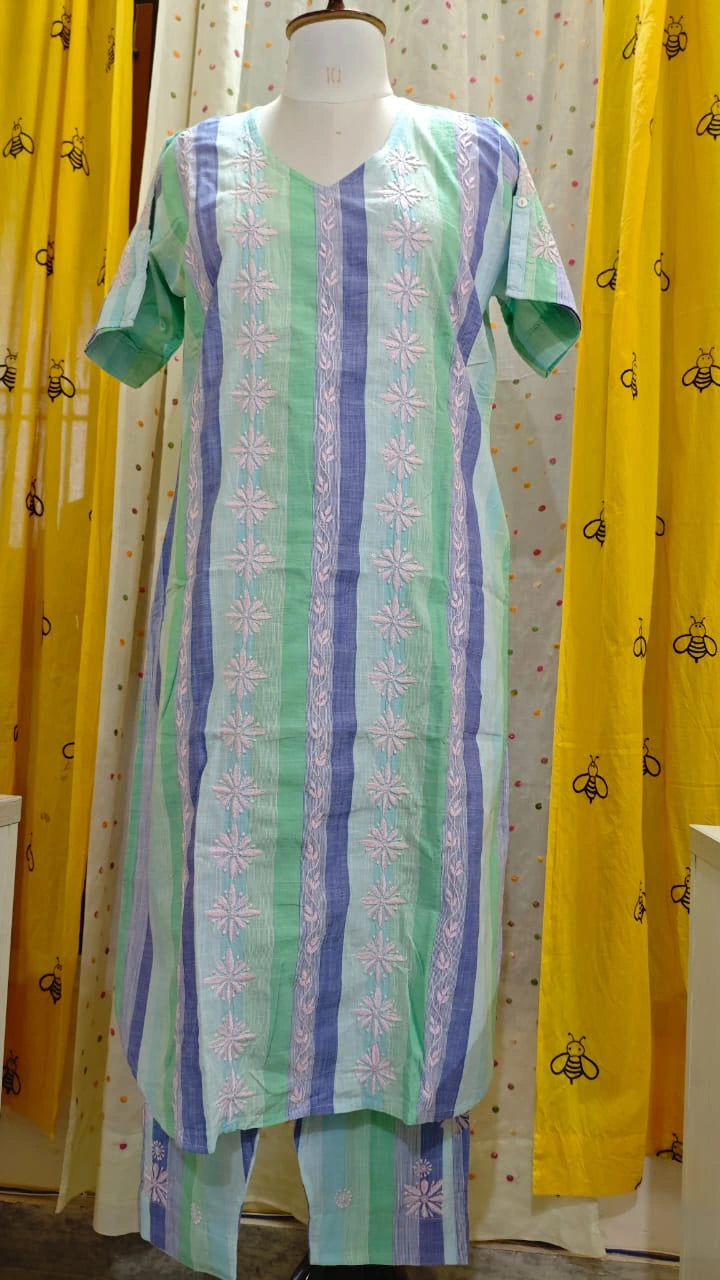 Mannequin wearing a green and blue patterned dress with yellow curtains in the background