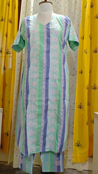 Mannequin wearing a green and blue patterned dress with yellow curtains in the background