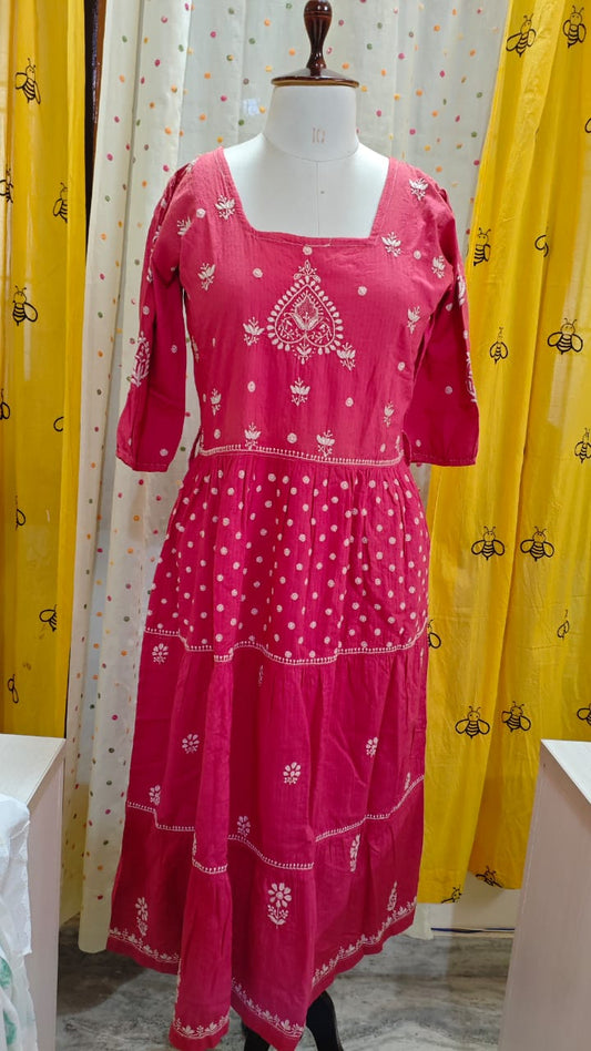 Pink traditional outfit with white  Chikankari patterns on a mannequin against yellow curtains.
