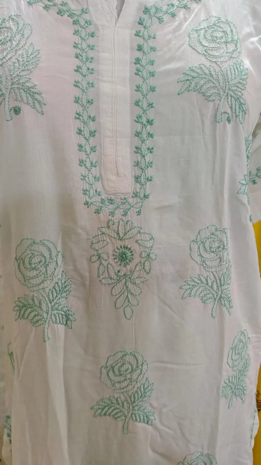 White garment with green chikankari embroidery on a white background