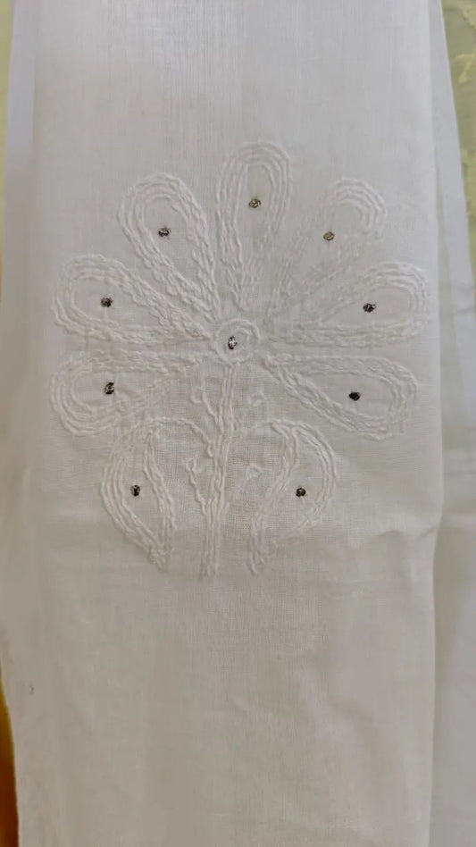 White fabric with floral embroidery and black beads on a yellow background