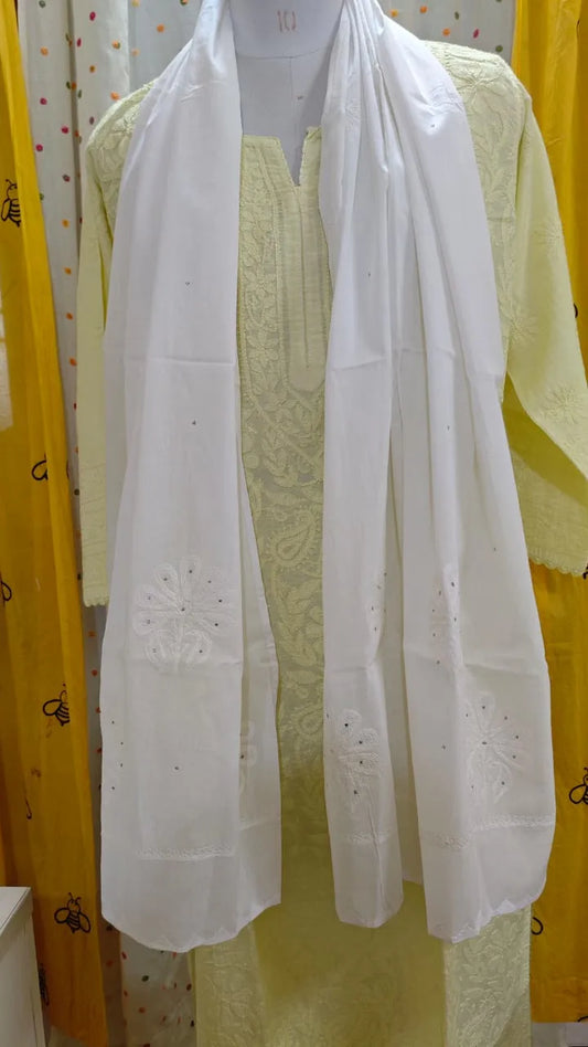White embroidered scarf draped over a yellow garment with yellow curtains in the background