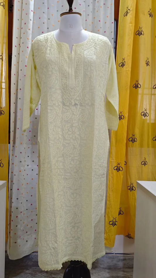 Light Yellow embroidered kurta on a mannequin against a yellow curtain with black patterns.