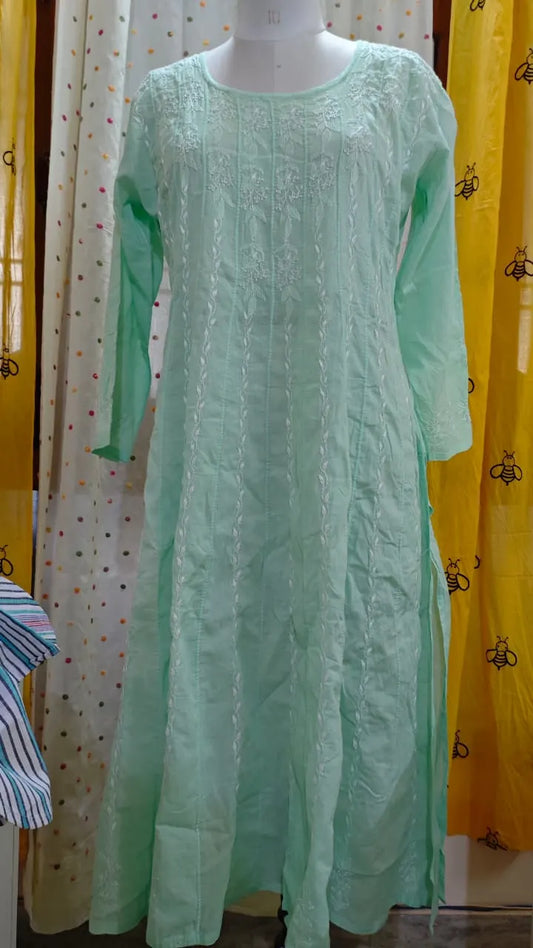 Light green embroidered Chikankari dress on a mannequin against a yellow curtain background