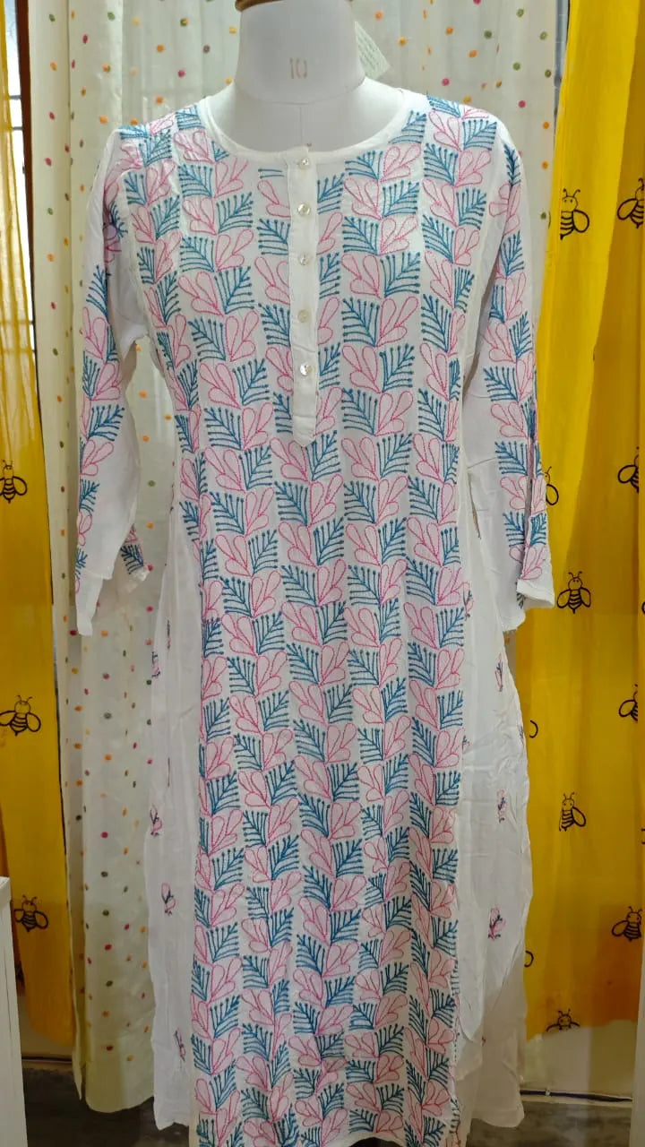 Long dress with leaf  Chikankari pattern on a mannequin against a yellow curtain background