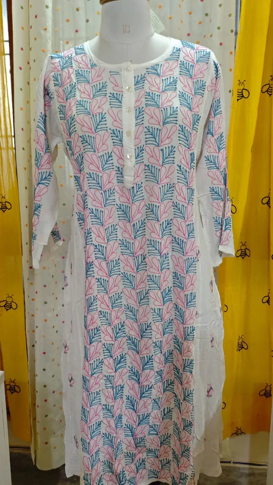 Long dress with leaf  Chikankari pattern on a mannequin against a yellow curtain background