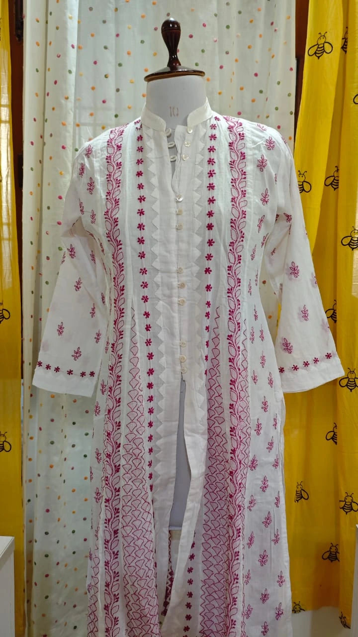 White  Chikankari embroidered kurta on a mannequin against a yellow and white patterned curtain background