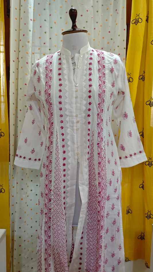 White  Chikankari embroidered kurta on a mannequin against a yellow and white patterned curtain background